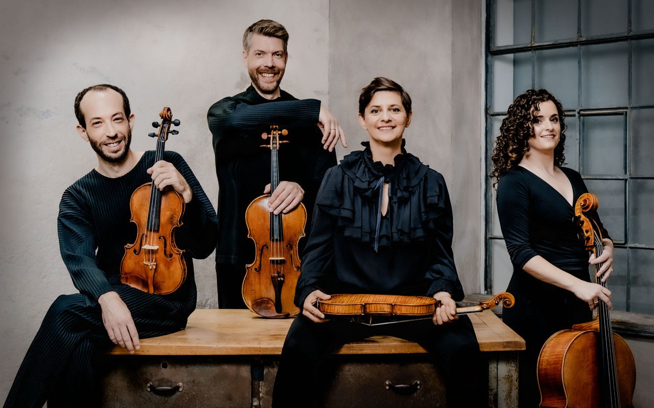 The Ariel Quartet poses in black clothing holding their instruments.
