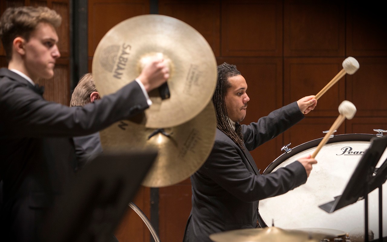 Percussion students perform on cymbals and drum with the wind ensemble in Corbett Auditorium
